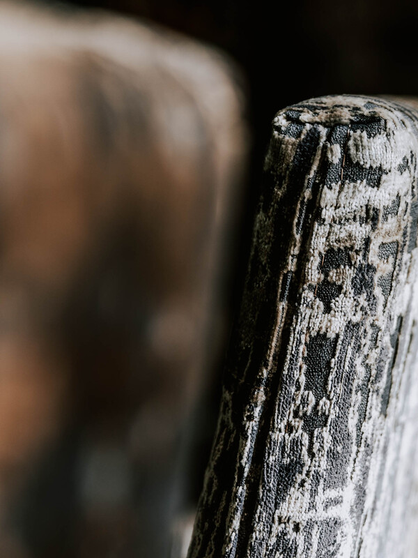 Nahaufnahme der gemusterten Stoffecke eines Stuhls, mit einem anderen Stuhl im Hintergrund.