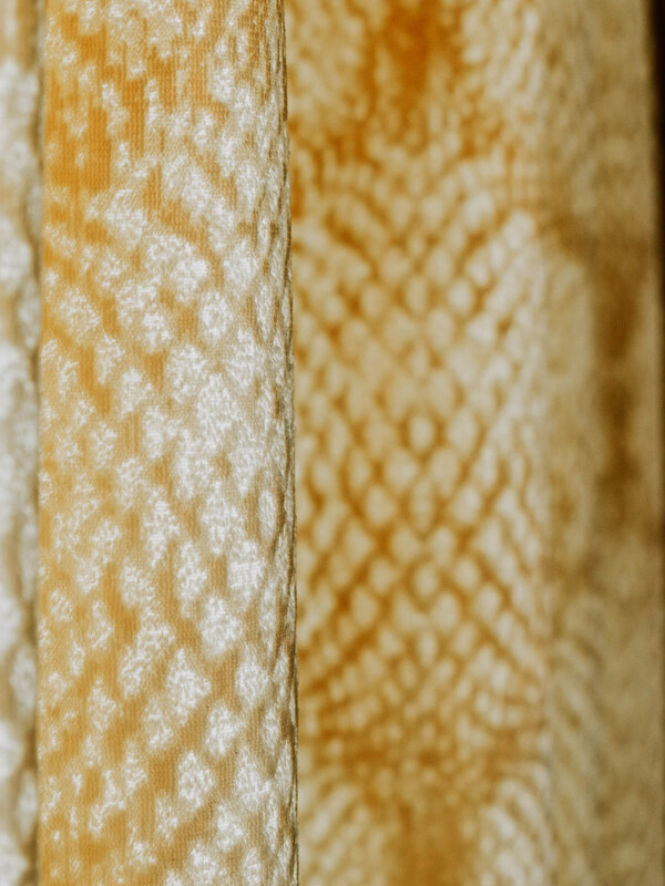 Nahaufnahme eines gelben und weißen strukturierten Stoffes mit einem sich wiederholenden Rautenmuster.