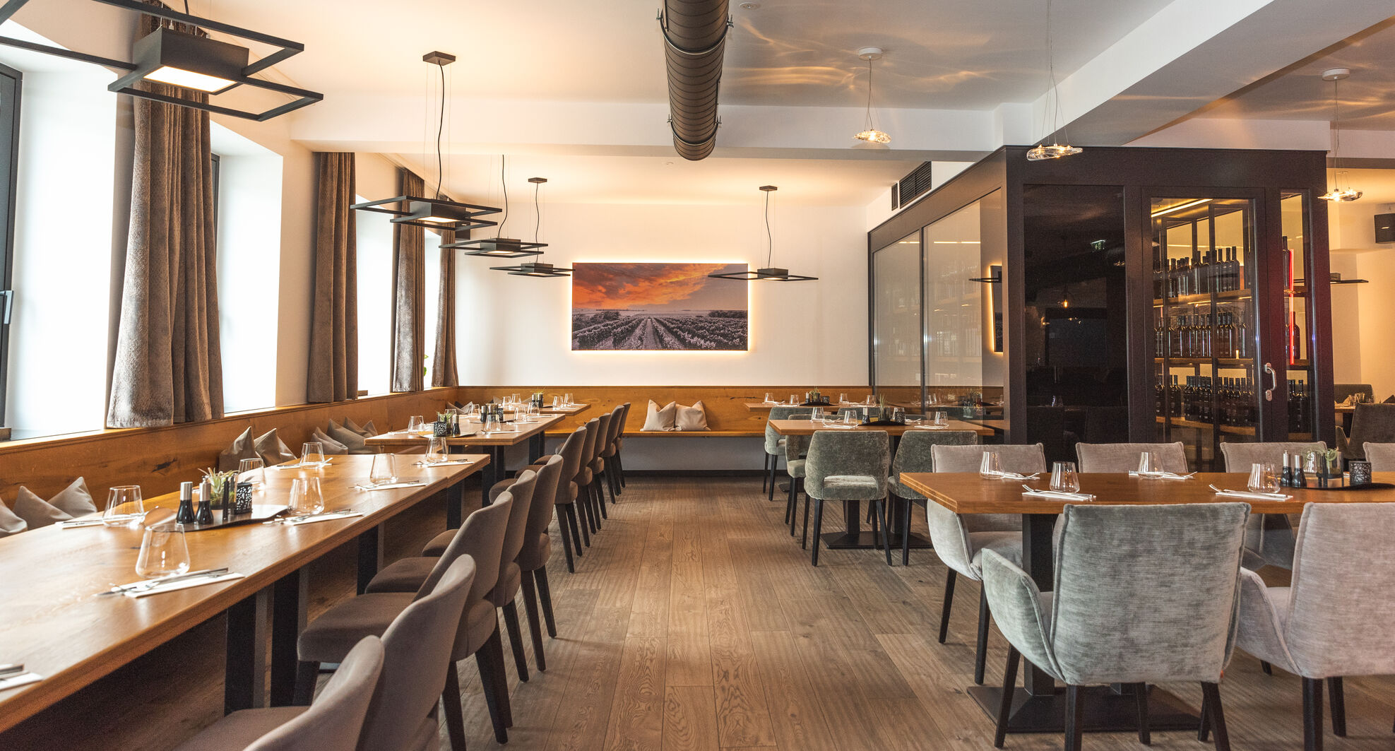 Modernes Restaurant mit Holzboden, gedeckten Tischen und einem großen Landschaftsfoto an der Wand.
